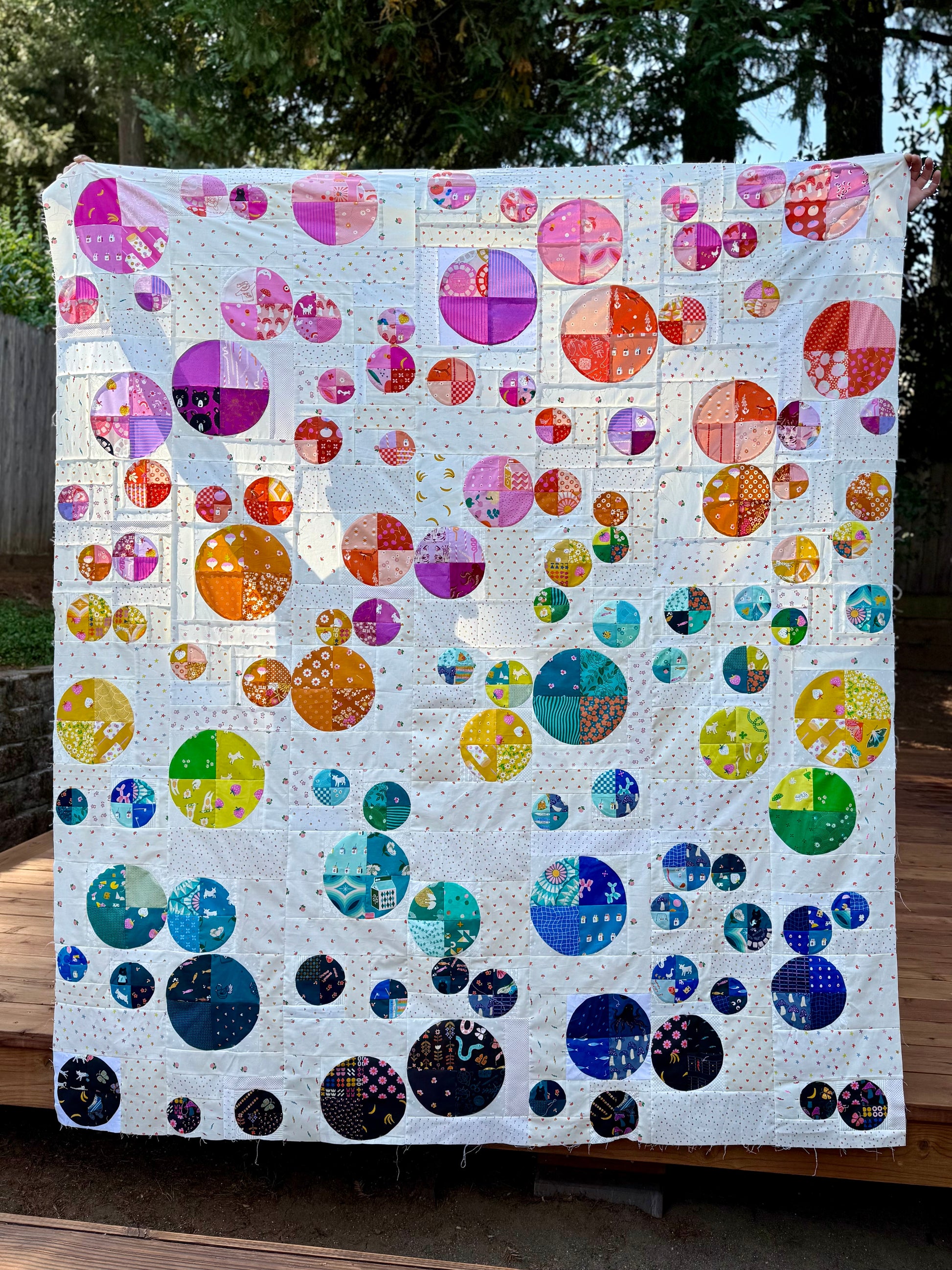 Colorful quilt with circular patterns displayed outdoors.