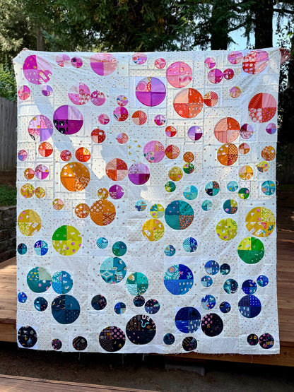 Colorful quilt with circular patterns displayed outdoors.