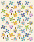 A quilt with a pinwheel pattern, featuring multiple colors and a 45-degree rotation, creating a whimsical and modern look.